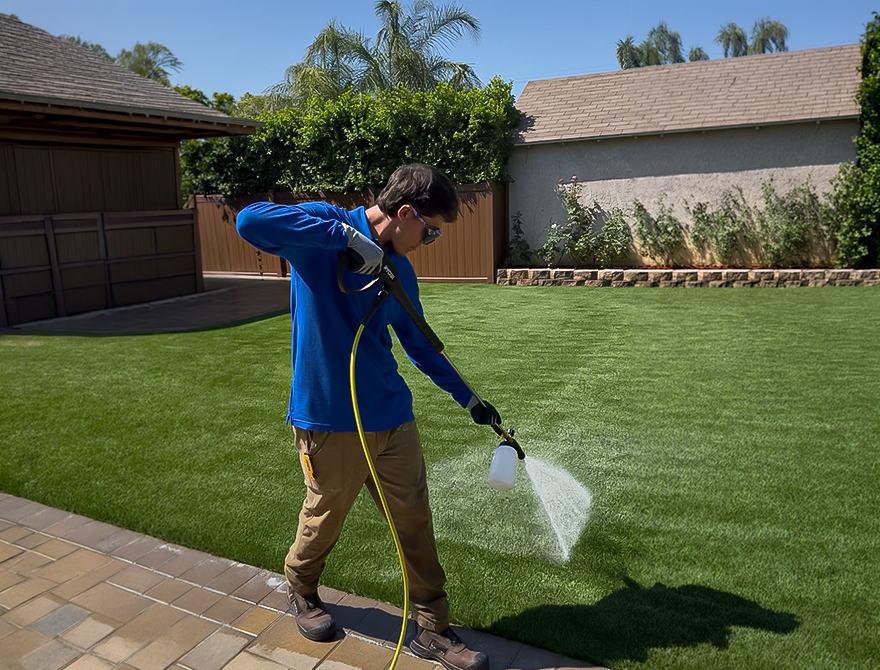 The Doggo Scoop technician applying a pet-safe sanitizing treatment to artificial turf